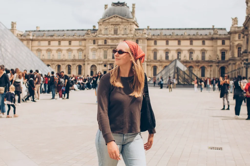 mujer turista con pañuelo rojo y gafas de sol en el louvre de parís